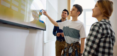 Student touching screen of mounted interactive panel while others look on
