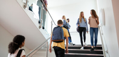 High school age students walking in stairwell in campus building